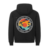Der schwarze Premium Hoodie "Urlaub" von MarketPrint hat eine lockere Passform und zeigt eine kreisförmige Sonnenuntergangs-, Palmen- und Wassergrafik mit "KOMM * MACH * MAL * URLAUB" in weiß. Hergestellt in Türkiye.
