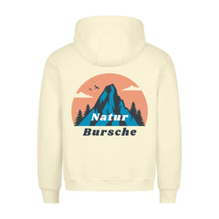 Der Premium Hoodie "Natur Bursche" von MarketPrint hat einen cremefarbenen, gemütlichen Schnitt und eine Rückengrafik mit Bergen, Bäumen, Vögeln, Wolken, sowie blauem und schwarzem "Natur Bursche"-Text. Hergestellt in Türkiye für Komfort und Stil.