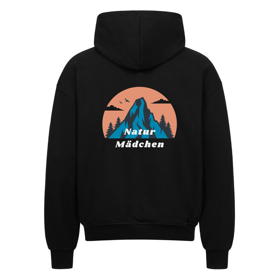 Der schwarze Oversized Zipper Hoodie "Natur" von MarketPrint zeigt eine Rückengrafik mit einem blauen Berg, Vögeln und Bäumen in einem pfirsichfarbenen Kreis mit "Natur Mädchen" in weiß. Hergestellt aus 100% Baumwolle für Komfort.