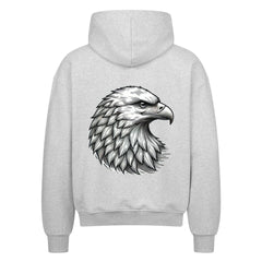 Der Oversized Zipper Hoodie "Adler" von MarketPrint in Grau zeigt eine detaillierte schwarz-weiße Illustration eines Adlerkopfes mit auffälligen Federn auf dem Rücken, alles vor einem weißen Hintergrund.