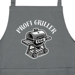 Die MarketPrint Latzschürze "PROFI-GRILLER" in Grau zeigt eine schwarz-weiße Grill-Illustration mit frechem PROFI GRILLER-Schriftzug - ideal zum Schutz der Kleidung beim Grillen oder bei der Gartenarbeit.