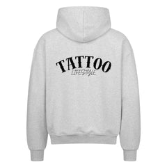 Der MarketPrint Oversized Zipper Hoodie "TATTOO" in Hellgrau zeigt sich von hinten, mit großem schwarzem "TATTOO LIFESTYLE"-Text auf dem oberen Rücken und einem übergroßen Schnitt für eine entspannte Passform.