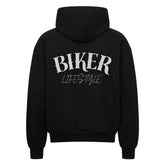 Der MarketPrint Oversized Zipper Hoodie "BIKER" in schwarz hat einen auffälligen weißen "BIKER LIFESTYLE"-Schriftzug auf dem Rücken, 100% Baumwolle und einen übergroßen Schnitt, der auf einem klaren weißen Hintergrund dargestellt ist.