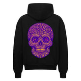 Der Oversized Zipper Hoodie "Totenkopf" von MarketPrint ist ein schwarzer Kapuzenpulli aus 100% Baumwolle mit einem verschnörkelten lila-goldenen Totenkopf-Motiv, das auf der Rückseite mit komplizierten Blumen- und Wirbelmustern versehen ist.