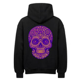 Der MarketPrint Oversized Hoodie "Totenkopf" in Schwarz zeigt einen auffälligen lila-goldenen Totenkopf mit floralen Mustern und detaillierten Ornamenten auf der Rückseite für einen auffälligen Look.