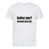 Das Premium Shirt "Steht Still" von MarketPrint ist ein schlichtes weißes Unisex-T-Shirt aus weicher Bio-Baumwolle mit schwarzem Text "Kaffee leer? Baustelle steht still." mittig auf der Vorderseite.