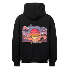 Der Oversized Hoodie "Sonnenuntergang" von MarketPrint ist ein schwarzer, schwerer Baumwoll-Kapuzenpullover mit übergroßer Passform, der ein farbenfrohes Sonnenuntergangsbild in Pink, Orange und Lila mit Wolken und Bäumen auf dem Rücken zeigt.