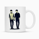 Die MarketPrint Tasse "Mann-Mann" ist eine weiße Keramiktasse mit Duraglaze-Beschichtung, die zwei Männer Hand in Hand zeigt, beide in langen Ärmeln und Hosen, ohne Gesichtszüge. Perfekt als Sublimationstasse geeignet.