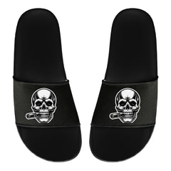 Die MarketPrint Badelatschen "Totenkopf" sind schwarze PVC-Rutschen mit einem Totenkopf und einer Zigarre auf jedem oberen Riemen - ideal für Ihren nächsten Badetag.