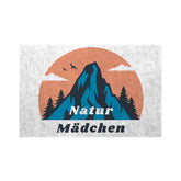 Illustration von einem Berg, Bäumen, zwei Vögeln und Wolken auf einem orangefarbenen Kreis mit "Natur Mädchen" in blau und schwarz. Die MarketPrint Fußmatte hält Schmutz abhalten und Ihren Eingangsbereich sauber.