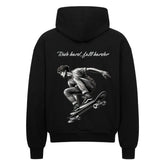 Der Oversized Zipper Hoodie "Fall hard, fall harder" von MarketPrint ist ein schwarzer Premium-Zip-up mit einer weißen Skateboard-Illustration in der Mitte des Sprungs und dem Text "Ride hard, fall harder" auf der Rückseite.