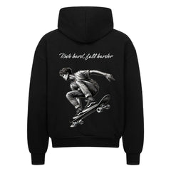 Der Oversized Zipper Hoodie "Fall hard, fall harder" von MarketPrint ist ein schwarzer Premium-Zip-up mit einer weißen Skateboard-Illustration in der Mitte des Sprungs und dem Text "Ride hard, fall harder" auf der Rückseite.