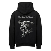 Der Oversized Hoodie "Ride Hard" von MarketPrint ist schwarz und zeigt eine Skateboard-Illustration in der Mitte des Sprungs mit dem Text "Ride hard, fall harder" darüber.