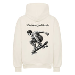 Der Oversized Hoodie "Ride Hard" von MarketPrint ist ein weißer Kapuzenpulli aus schwerer Baumwolle, der einen skatenden Mann zeigt. Die übergroße Passform sorgt für Komfort und Streetstyle.