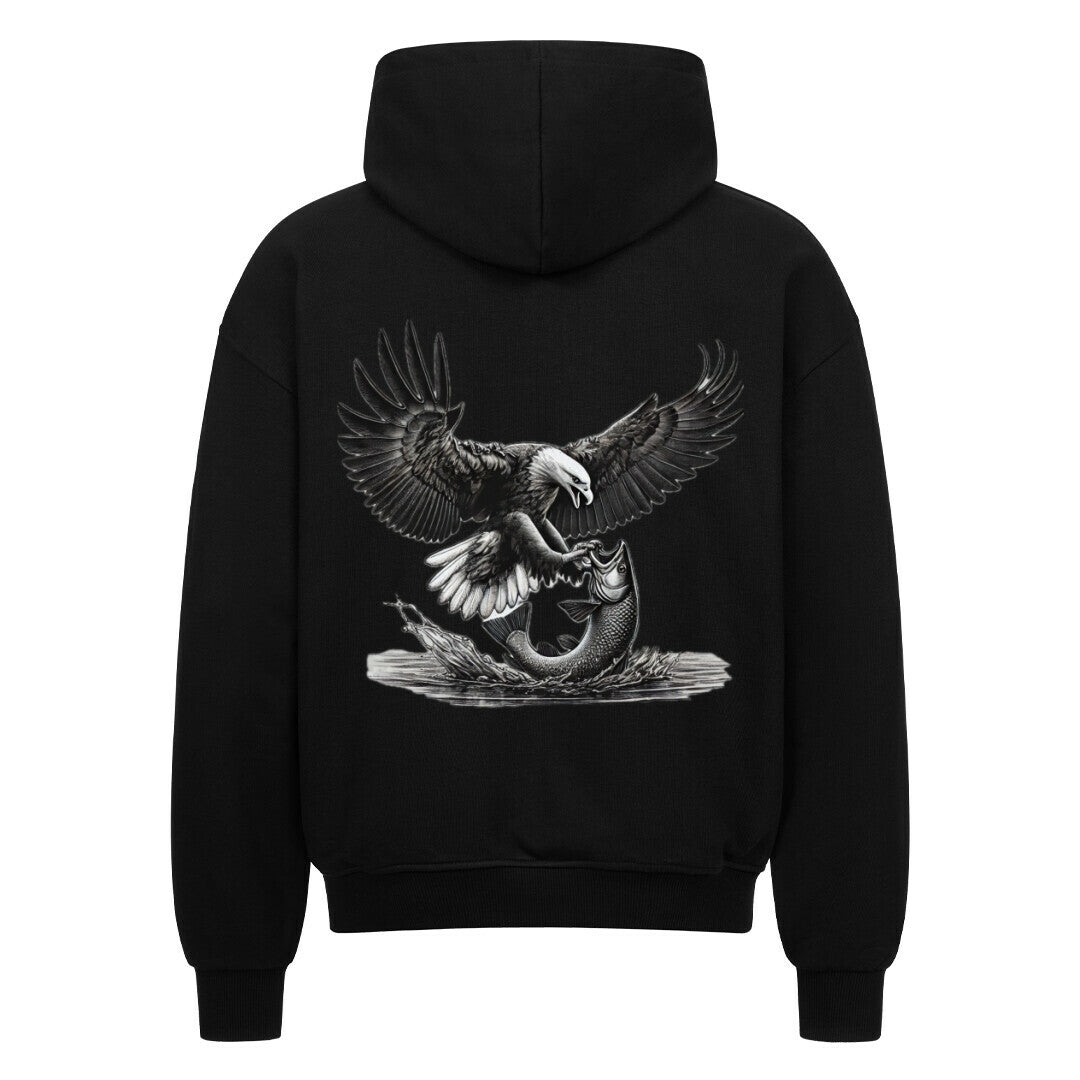 Der MarketPrint Oversized Zipper Hoodie "Adler-fisch" in schwarz zeigt auf der Rückseite eine detaillierte Illustration eines Weißkopfseeadlers, der sich im Sturzflug einen Fisch fängt. Das Ganze in einer bequemen Oversized-Passform.