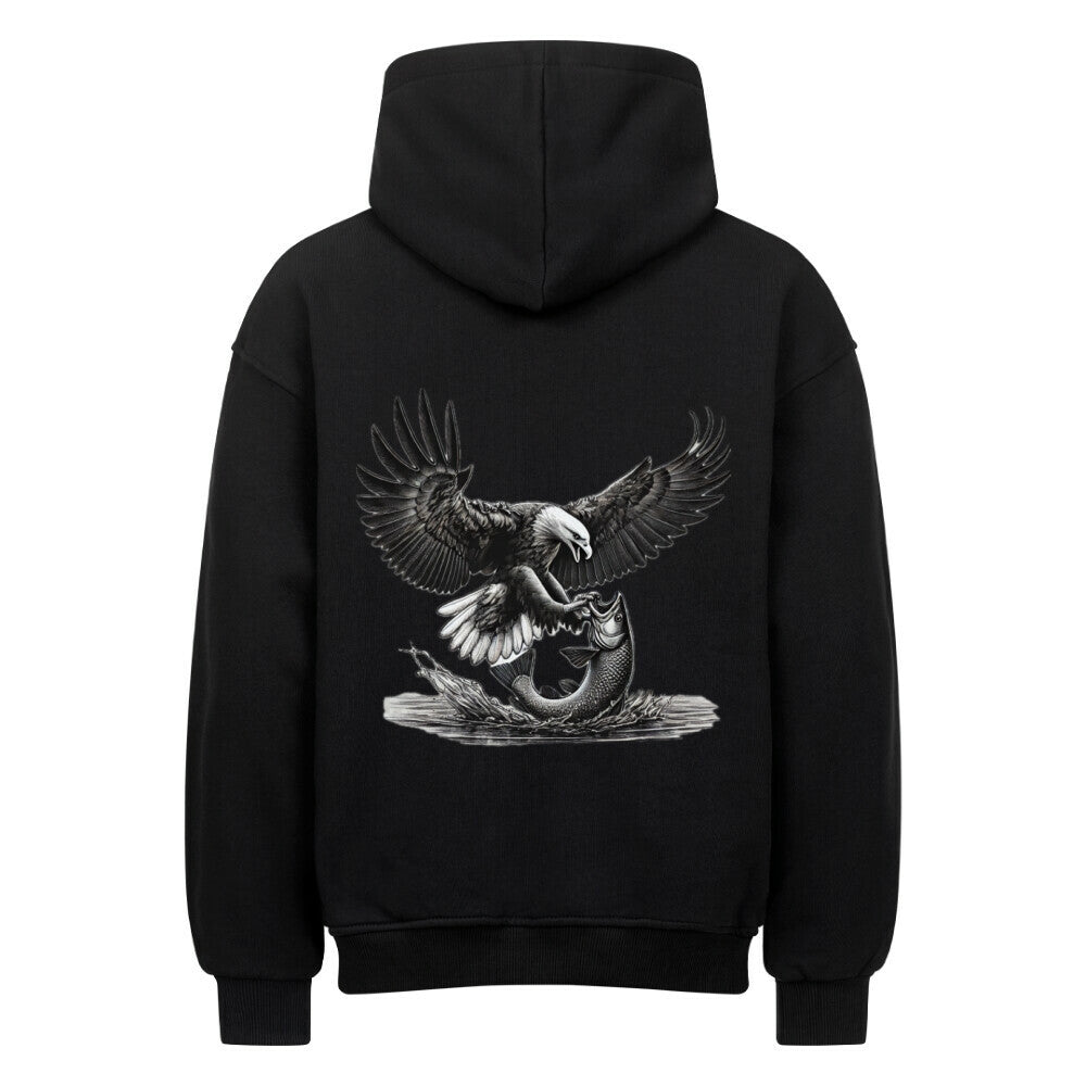 Der MarketPrint Oversized Hoodie "Adler-Fisch" ist ein schwarzer Kapuzenpulli aus schwerer Baumwolle mit einer auffälligen Rückengrafik, die einen Weißkopfseeadler zeigt, der sich mit ausgestreckten Krallen auf einen Fisch stürzt.