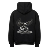 Der MarketPrint Oversized Hoodie "Adler-Fisch" ist ein schwarzer Kapuzenpulli aus schwerer Baumwolle mit einer auffälligen Rückengrafik, die einen Weißkopfseeadler zeigt, der sich mit ausgestreckten Krallen auf einen Fisch stürzt.