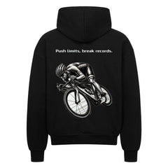 Der Oversized Zipper Hoodie "Radsport" von MarketPrint ist ein schwarzer Premium-Kapuzenpullover mit einer Graustufen-Radfahrergrafik und dem Slogan "Push limits, break records." darüber auf dem Rücken.