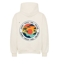 Der Oversized Hoodie "Urlaub" von MarketPrint ist ein cremefarbener Premium-Kapuzenpulli mit einer großen kreisförmigen Sonnenuntergangs-, Palmen-, Meeres- und Vogelgrafik auf dem Rücken und KOMM * MACH * MAL * URLAUB-Text. Kombiniert Komfort und Stil.