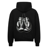 Der Oversized Zipper Hoodie "Boxhandschuhe" von MarketPrint ist ein schwarzer Kapuzenpulli mit einer auffälligen Boxhandschuh-Illustration auf dem Rücken. Der Hoodie hat eine übergroße Passform und ist aus 100% Baumwolle für Komfort und Stil gefertigt.