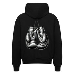 Der Oversized Zipper Hoodie "Boxhandschuhe" von MarketPrint ist ein schwarzer Kapuzenpulli mit einer auffälligen Boxhandschuh-Illustration auf dem Rücken. Der Hoodie hat eine übergroße Passform und ist aus 100% Baumwolle für Komfort und Stil gefertigt.