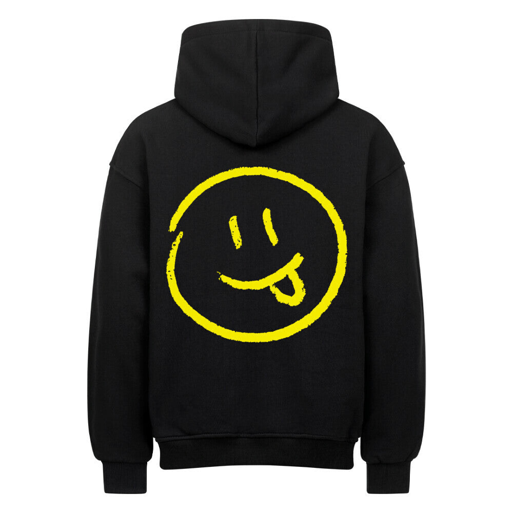 Der MarketPrint Oversized Hoodie "Smiley" ist ein schwarzer Premium-Kapuzenpullover mit einem großen, handgezeichneten gelben Smiley-Gesicht mit herausgestreckter Zunge auf dem Rücken, umrandet von einem gelben Kreis.