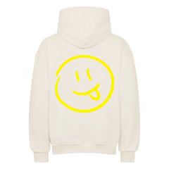 Der MarketPrint Oversized Hoodie "Smiley" ist cremefarben mit einer großen gelben Smiley-Grafik, mit herausgestreckter Zunge, auf dem Rücken.