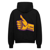 Der Oversized Zipper Hoodie "Daum hoch" von MarketPrint ist ein schwarzer Kapuzenpulli mit einer großen gelben Daumen-hoch-Grafik auf dem Rücken, die lila umrandet ist.