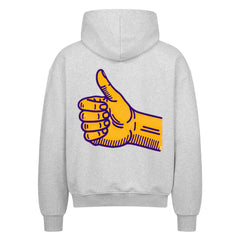 Der MarketPrint Oversized Zipper Hoodie "Daum hoch" ist ein graues Sweatshirt aus 100% Baumwolle mit einer großen gelben, lila umrandeten Daumen-hoch-Hand-Grafik auf dem Rücken, die auf einem weißen Hintergrund abgebildet ist.