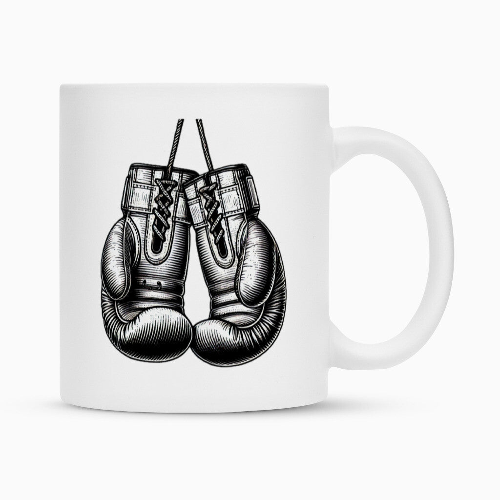 Die MarketPrint Tasse "Box-Handschuhe" ist eine weiße Keramiktasse mit detaillierten schwarz-weißen Boxhandschuhen, die sich dank ihrer hochwertigen Duraglaze-Beschichtung ideal als Sublimationstasse eignet.