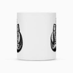 Die MarketPrint Tasse "Box-Handschuhe" ist eine weiße Keramik Tasse mit zwei partiellen schwarz-weißen Abbildungen einer sitzenden, gewandeten Figur, die nach außen zeigt. Die zentrale leere Fläche ermöglicht eine individuelle Gestaltung und sie verfügt über eine langlebige Duraglaze Beschichtung.