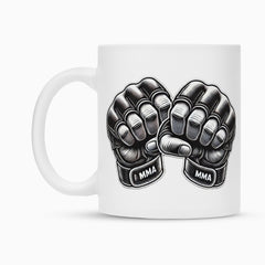 Die Tasse "MMA" von MarketPrint ist eine weiße Keramiktasse mit zwei schwarzen MMA-Handschuhen, erhobenen Fäusten und dem Schriftzug "MMA" auf den Trägern - eine stylische Sublimationstasse, perfekt für Kampfsportfans.