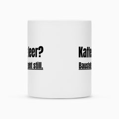 Eine weiße Sublimationstasse "Kaffee" von Infinity Merch mit Duraglaze-Beschichtung zeigt teilweise fett schwarzen deutschen Text wie "Kaffee", "leer?" und "asteht still.", sichtbar durch den Winkel.