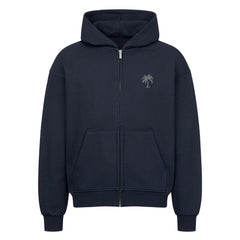 Der Infinity Merch Oversized Zipper Hoodie "Strand" in Marineblau verfügt über eine Kapuze, Vordertaschen und eine kleine Palmengrafik auf der linken Brust. Hergestellt aus 100% Baumwolle und auf einem einfarbig weißen Hintergrund abgebildet.