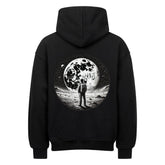 Der Infinity Merch Oversized Hoodie "Astro" in Schwarz mit der Rückengrafik eines Astronauten auf dem Mond unter einem Sternenhimmel und einem großen Mond kombiniert erstklassigen Komfort mit einem auffälligen Weltraum-Stil.