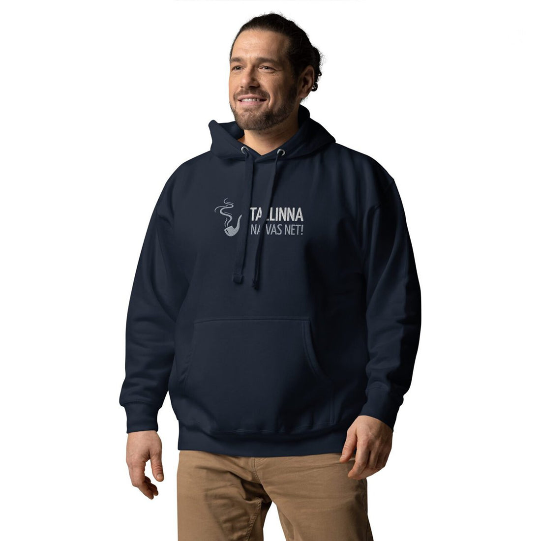Eine Person steht vor einem weißen Hintergrund und trägt einen dunklen Kapuzenpullover mit der Aufschrift TALLINNA NALVAS NET! und einer dampfenden Tasse auf der Vorderseite sowie eine hellbraune Hose.