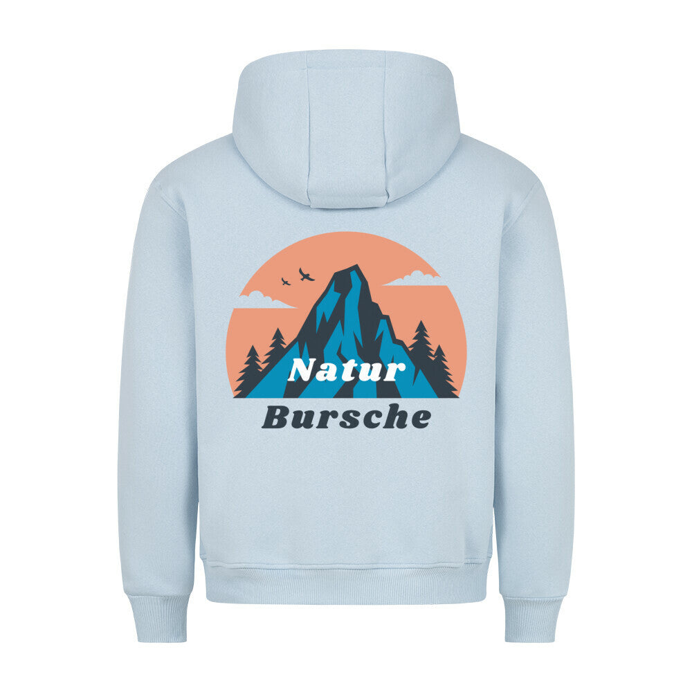 Der MarketPrint Premium Hoodie "Natur Bursche" in hellblau hat eine lockere Passform und zeigt eine Berg-, Baum-, Vogel- und Wolkengrafik mit einem orangefarbenen Kreis auf dem Rücken sowie den Text "Natur Bursche". Hergestellt in Türkiye.