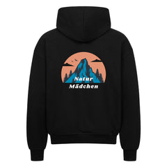 Der schwarze Oversized Zipper Hoodie "Natur" von MarketPrint zeigt eine Rückengrafik mit einem blauen Berg, Vögeln und Bäumen in einem pfirsichfarbenen Kreis mit "Natur Mädchen" in weiß. Hergestellt aus 100% Baumwolle für Komfort.