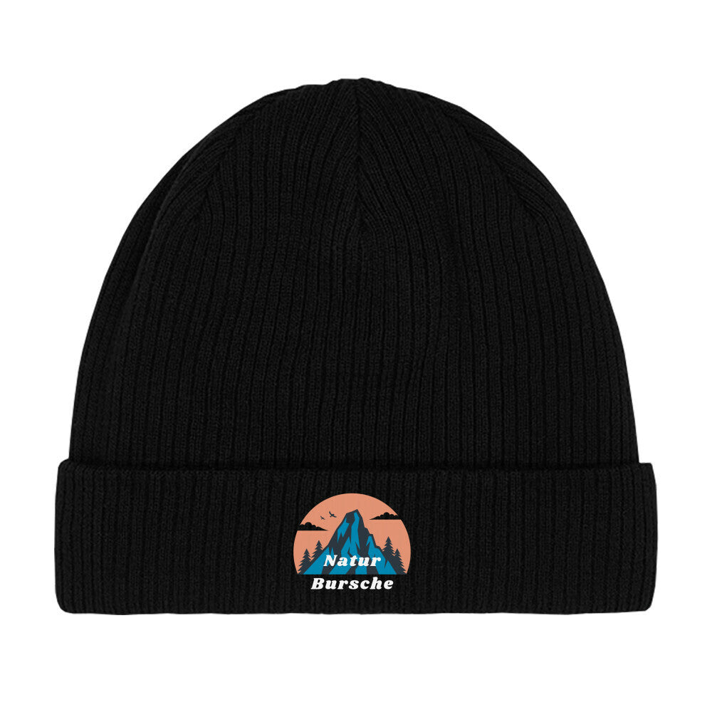 Die MarketPrint Beanie Mütze "Natur Bursche" ist eine schwarze, doppellagige Strick-Beanie mit Umschlag. Vorn ist ein Patch mit blauem Berg, Bäumen, Vögeln, orangefarbener Sonne und dem Schriftzug "Natur Bursche" in Weiß und Blau.