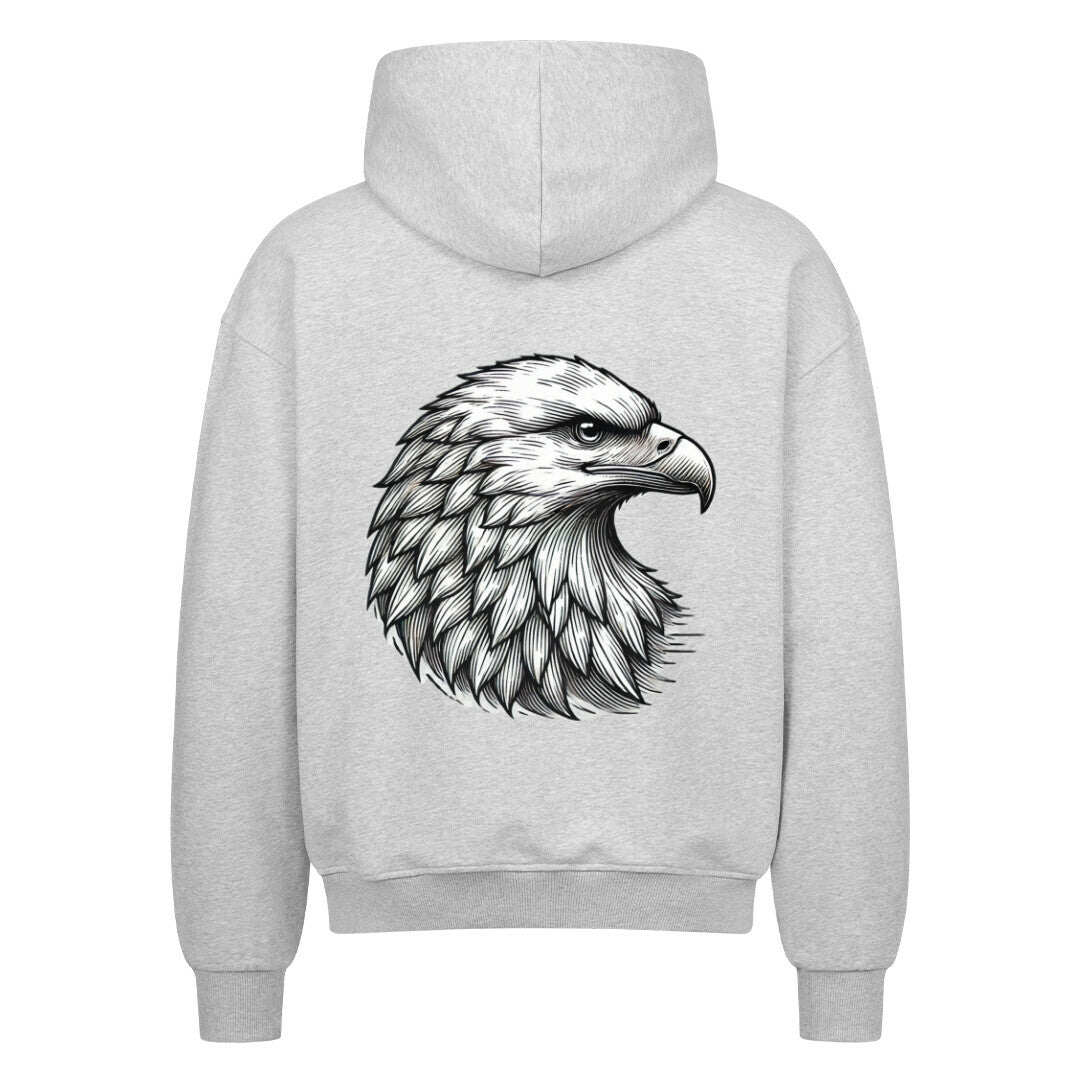 Der Oversized Zipper Hoodie "Adler" von MarketPrint in Grau zeigt eine detaillierte schwarz-weiße Illustration eines Adlerkopfes mit auffälligen Federn auf dem Rücken, alles vor einem weißen Hintergrund.