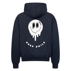 Der MarketPrint Oversized Zipper Hoodie "KEEP SMILE" in schwarz zeigt eine große schmelzende Smiley-Grafik und einen fetten weißen "KEEP SMILE"-Text auf der Rückseite. Hergestellt aus 100% Baumwolle für maximalen Komfort mit einer übergroßen Passform.