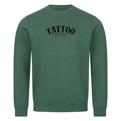 Das MarketPrint Premium Sweatshirt "TATTOO" ist ein unifarbenes, grünes Unisex-Sweatshirt aus weicher Bio-Baumwolle mit dem schwarzen Schriftzug "TATTOO LIFESTYLE" auf der Vorderseite. Es unterstreicht den nachhaltigen Stil mit langen Ärmeln und einem minimalistischen Design.