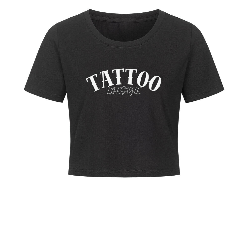 Das MarketPrint Ladies Cropped "Tattoo" ist ein schwarzes, kurz geschnittenes Damen-Shirt aus Baumwolle mit weißem TATTOO LIFESTYLE Schriftzug auf der Brust, präsentiert vor weißem Hintergrund.