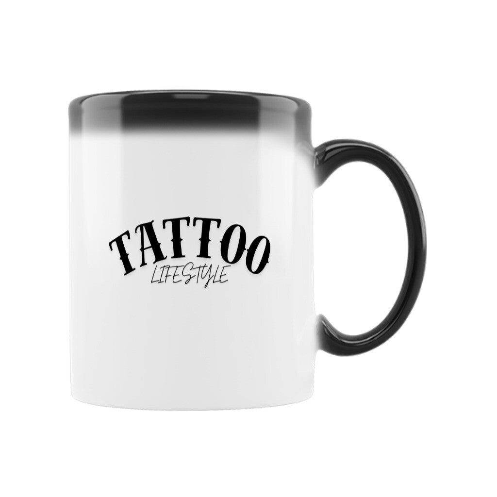 Die Zaubertasse "TATTOO" von MarketPrint ist eine weiße Keramiktasse mit schwarzem Farbverlauf an Rand und Henkel. Dank der Thermoeffekt-Tasse erscheint der stilisierte Text "TATTOO LIFESTYLE", wenn die Tasse die Farbe wechselt.