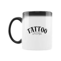 Die MarketPrint Zaubertasse "TATTOO" ist ein weißer Keramikbecher mit schwarzem Henkel und Rand. Beim Einfüllen von heißer Flüssigkeit kommt der Schriftzug "TATTOO LIFESTYLE" in schwarzer, stilisierter Schrift auf der Vorderseite zum Vorschein.