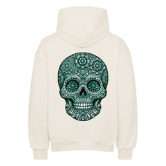 Der Oversized Hoodie "Totenkopf" von MarketPrint ist cremefarben, von hinten mit aufgesetzter Kapuze, und zeigt einen auffälligen grün-schwarzen Zuckerschädel mit Blumen- und Wirbelmustern, der seinen gemütlichen, hochwertigen Stil unterstreicht.