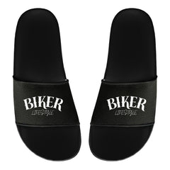 Ein Paar schwarze MarketPrint Badelatschen "Biker" mit weißem Schriftzug "BIKER LIFESTYLE" auf den Riemen, nebeneinander gestellt, mit der Vorderseite nach oben - perfekt für Ihren nächsten Badetag.