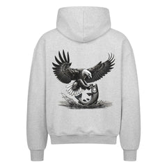 Der MarketPrint Oversized Zipper Hoodie "Adler-fisch" in Hellgrau zeigt auf der Rückseite eine detailreiche Adler-Grafik mit ausgebreiteten Flügeln, die einen Fisch über Wasser und Schilf umklammert.