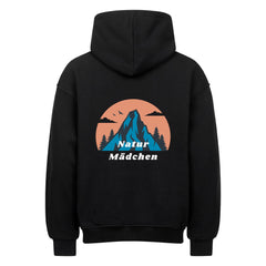 Der MarketPrint Oversized Hoodie "Natur" in schwarz hat eine erstklassige Passform mit einer Berg-, Baum-, Vogel- und orangefarbenen Himmelsgrafik auf dem Rücken und dem Aufdruck "Natur Mädchen" in Weiß darunter.