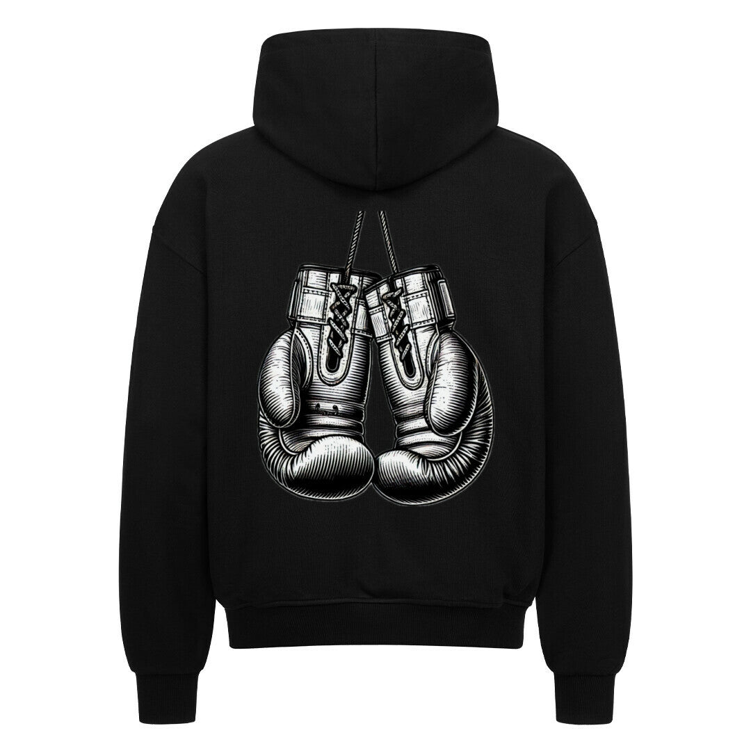 Der Oversized Zipper Hoodie "Boxhandschuhe" von MarketPrint ist ein schwarzer Kapuzenpulli mit einer auffälligen Boxhandschuh-Illustration auf dem Rücken. Der Hoodie hat eine übergroße Passform und ist aus 100% Baumwolle für Komfort und Stil gefertigt.
